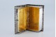 Caixa de comprimidos em prata em forma de livro com frisos gravados com interior dourado e tampa basculante.
